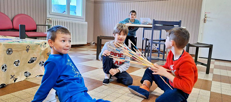 Trois garçons qui jouent aux mikados.